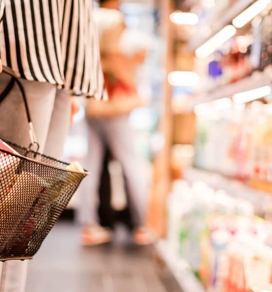 Eine Person hält einen Einkaufskorb in einem Supermarkt.