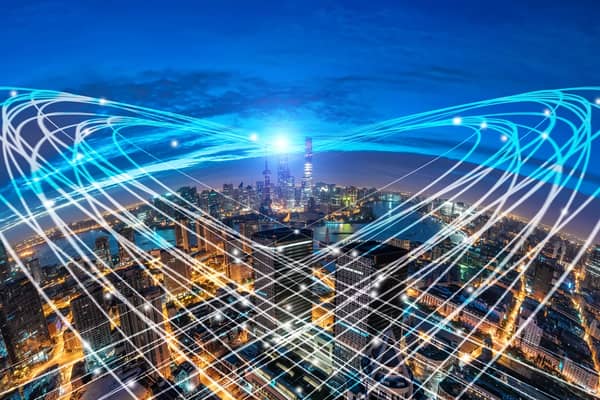 Stadt mit Wolkenkratzern die von Licht-Informationsstrahlen umgeben wird.