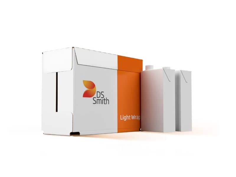 Umverpackung aus Wellpappe mit DS Smith Branding steht neben zwei weißen Getränkekartons