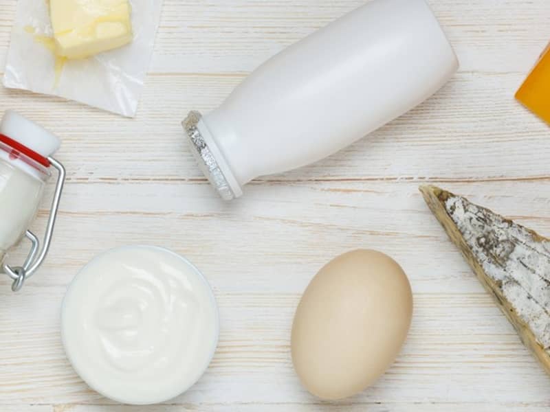 Auf einem Tisch stehen ein Ei, Milch, Käse und eine Schale Joghurt.