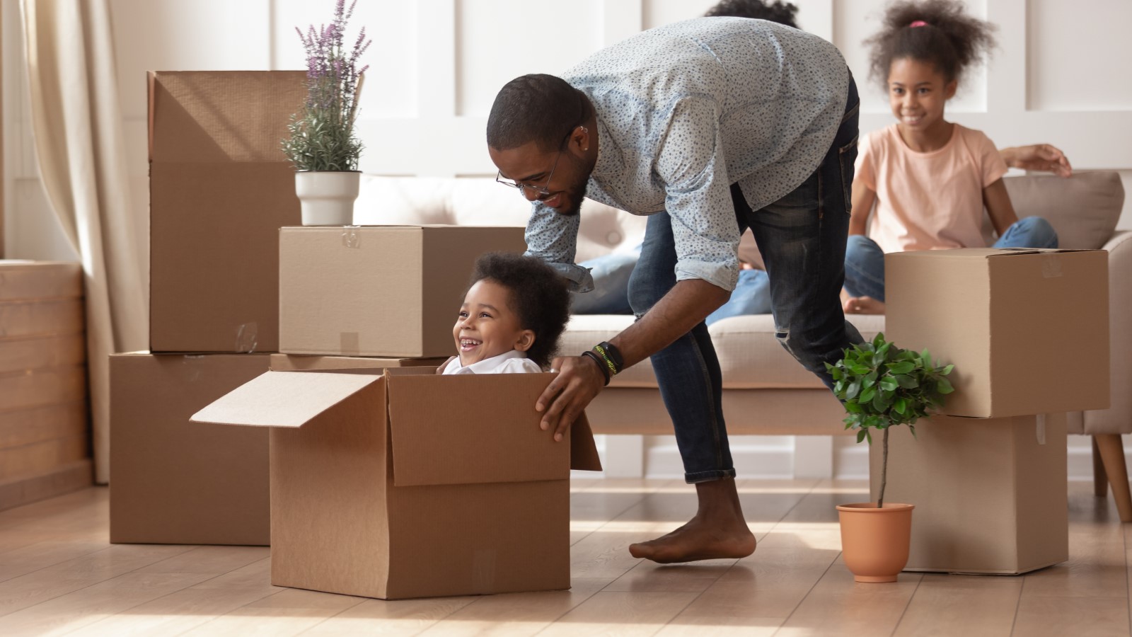 Mann spielt mit Kind in einer Box aus Wellpappe.