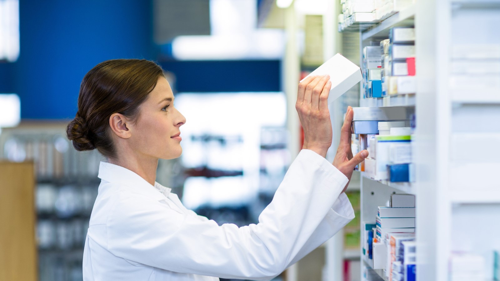 Eine Apothekerin holt eine Verpackung aus dem Regal.