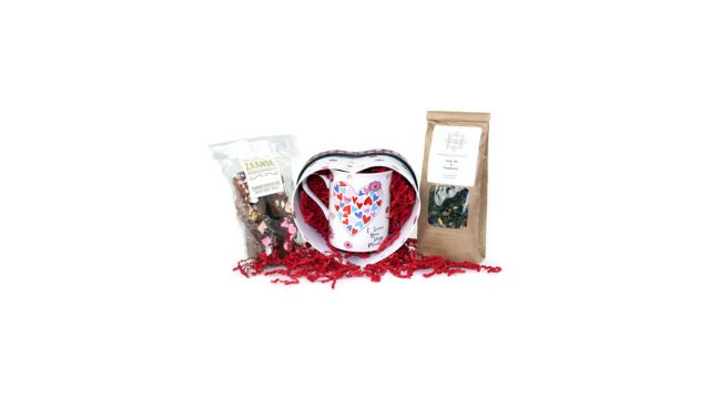 Een geschenkset van een koffiemok, bonbons en een hartvormig doosje met gekleurd sizzlepak opvulmateriaal