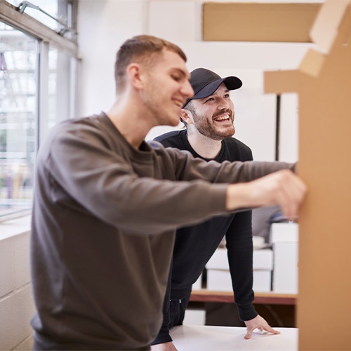 Two male graduates working on a cardboard display