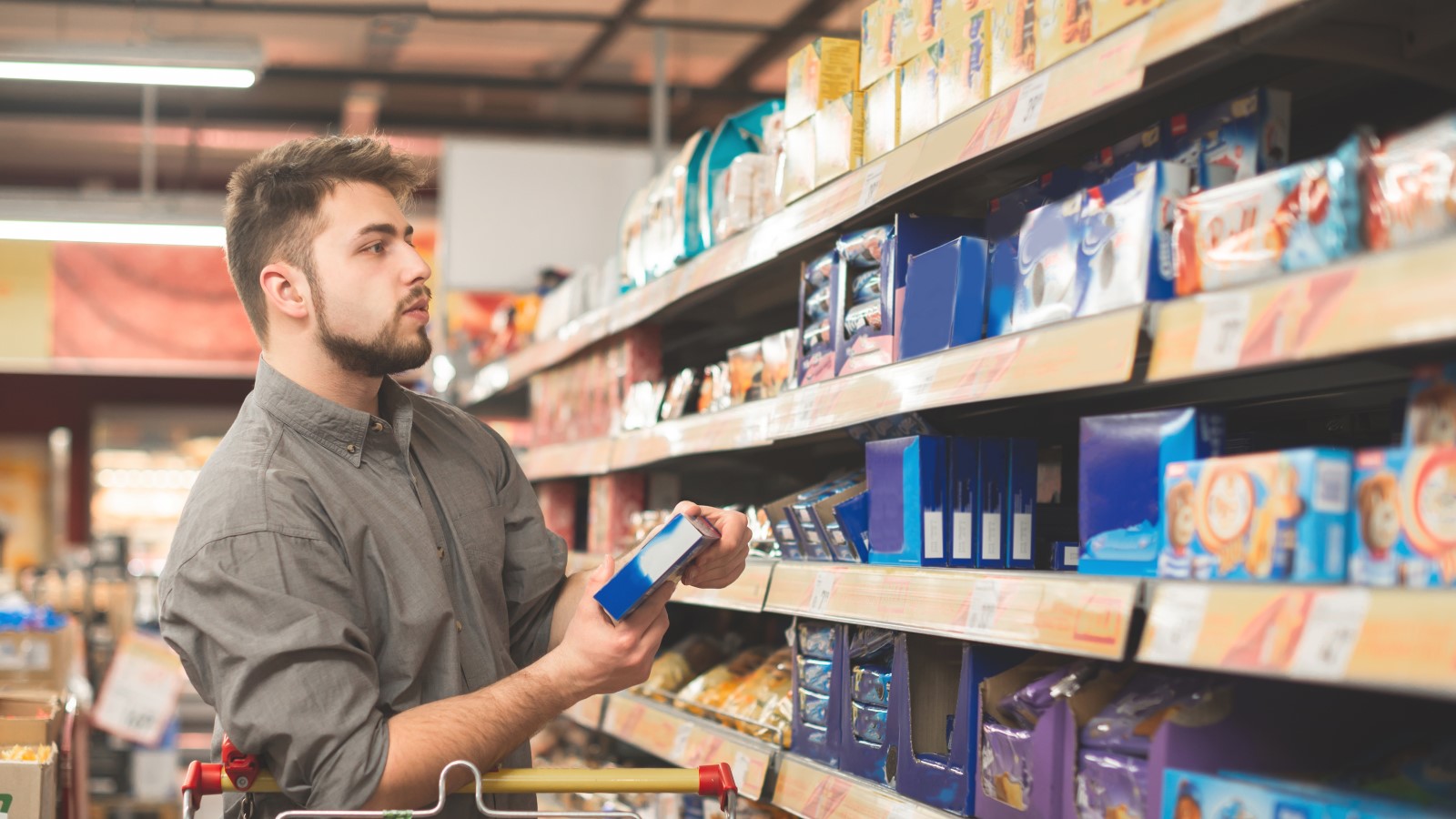 Mann steht im Supermarkt vor einem Regal.