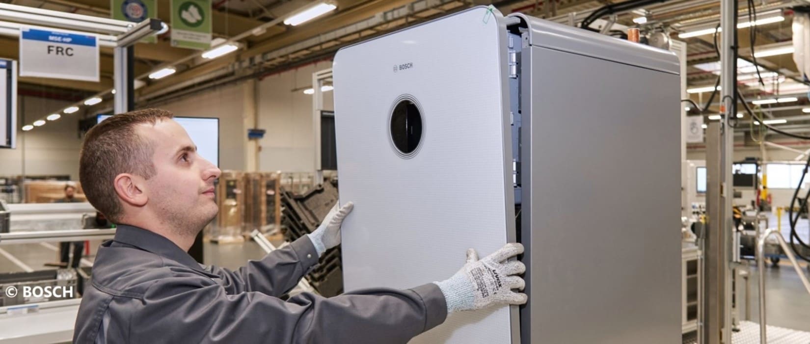 Mitarbeiter in der Produktion arbeitet daran eine weißer Gastherme von Bosch zusammenzusetzen