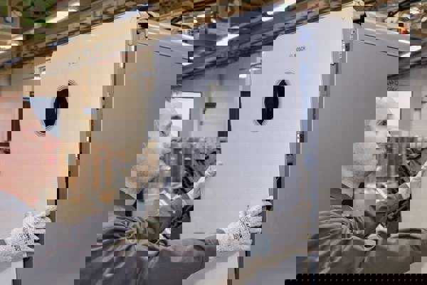 Mitarbeiter in der Produktion arbeitet daran eine weißer Gastherme von Bosch zusammenzusetzen