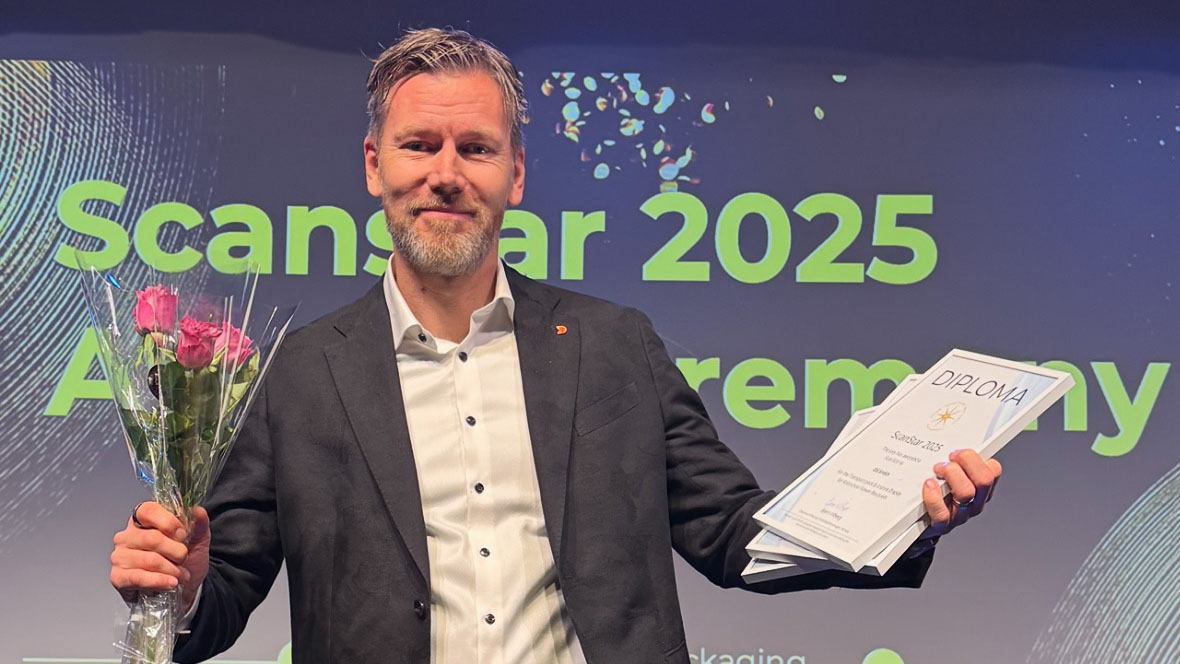 Mies kädessään kukka ja kunniokirjoja osoittamaan ScanStar palkintoja