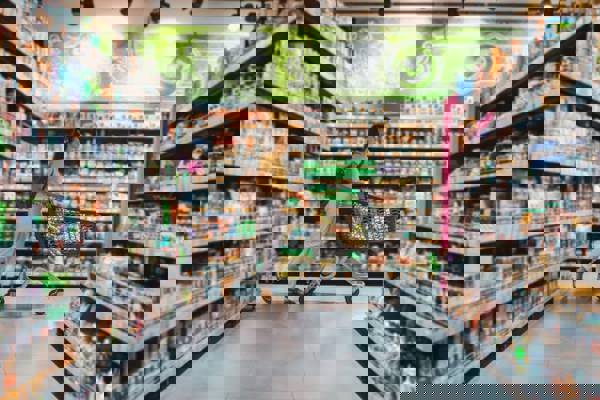 Frau im Supermarkt schiebt gefüllten Einkaufskorb