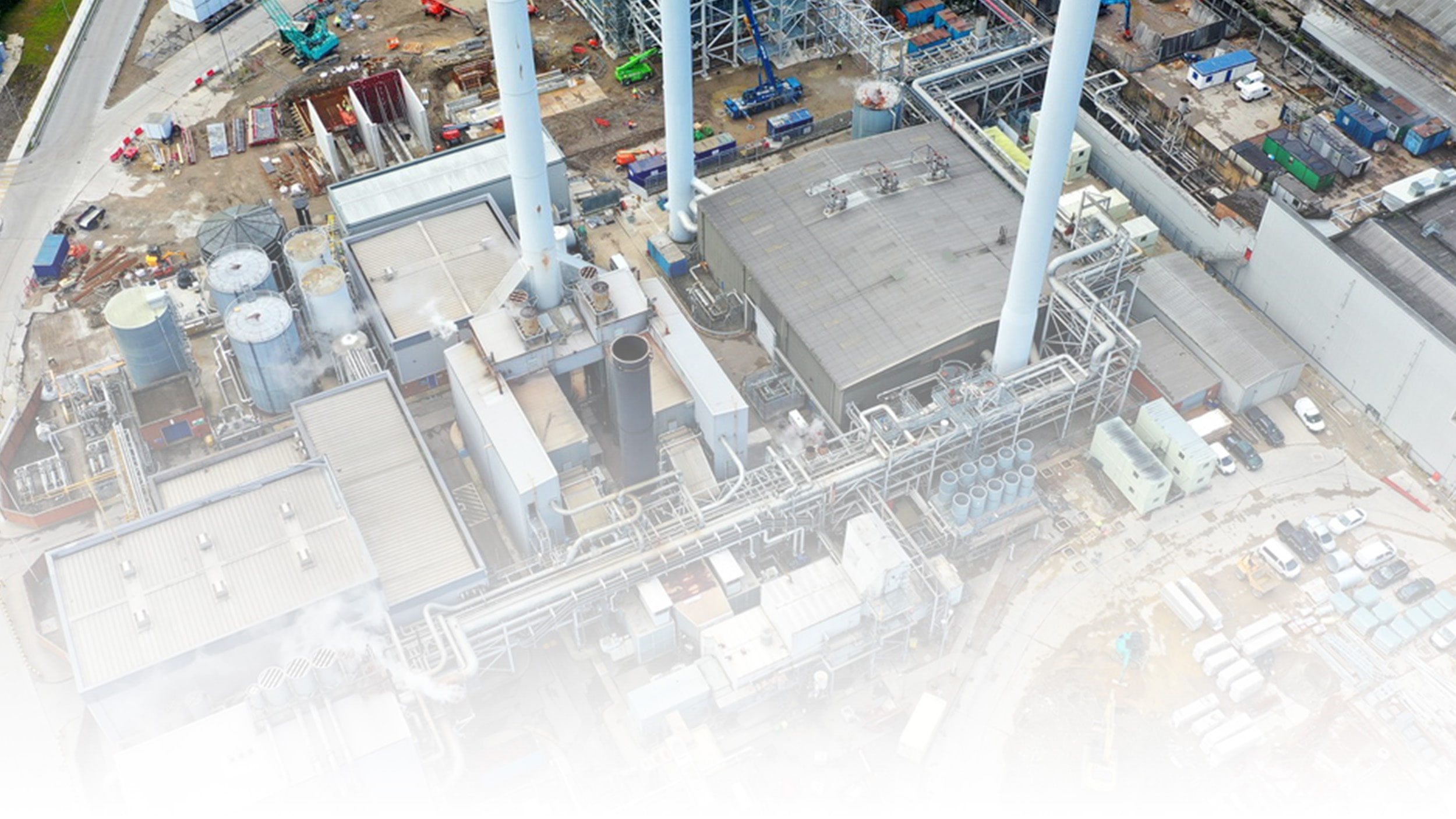 Luchtfoto van een industriële productielocatie met pijpleidingen, opslagtanks, gebouwen.