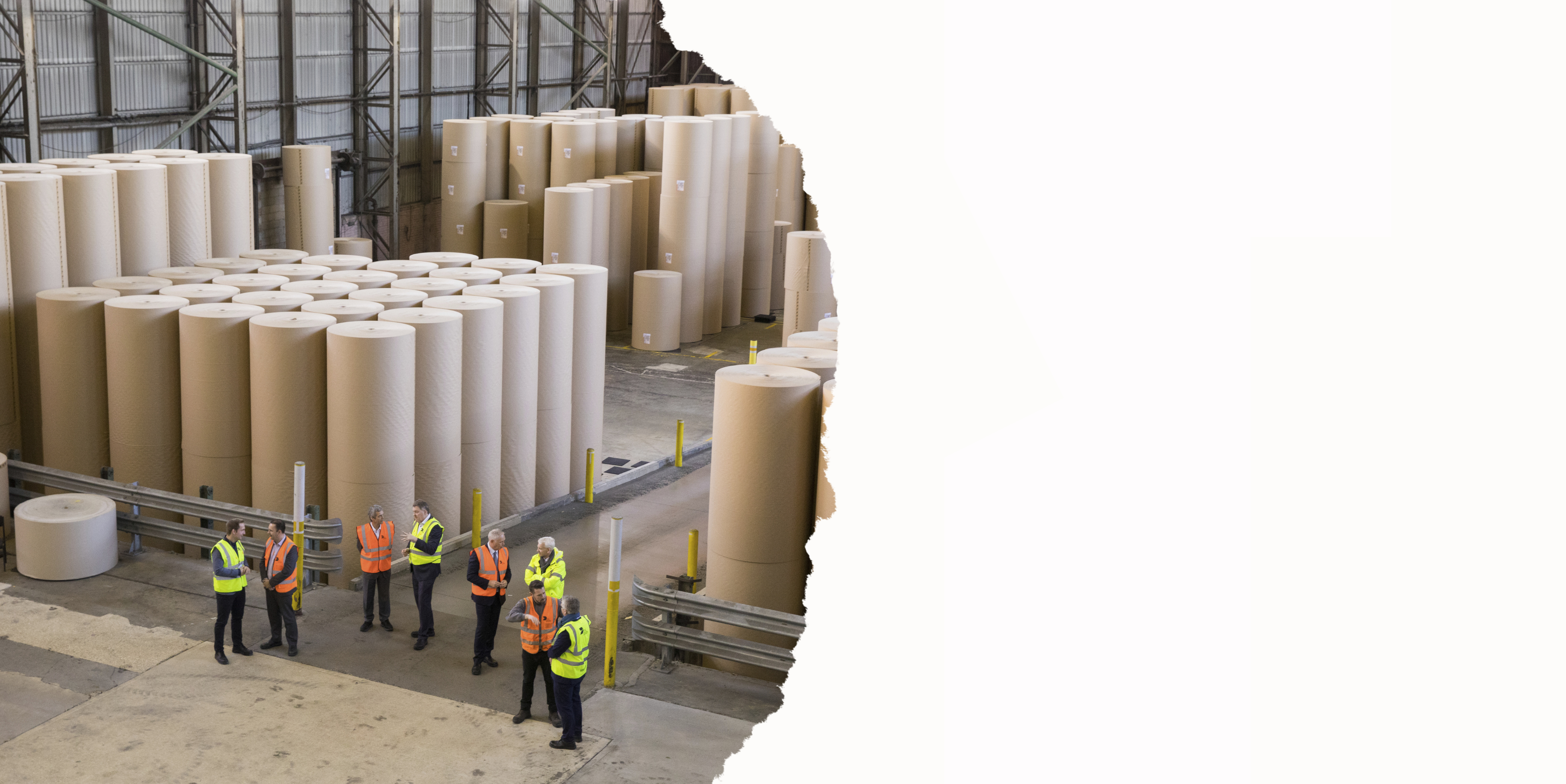 People standing next to giant reels of paper