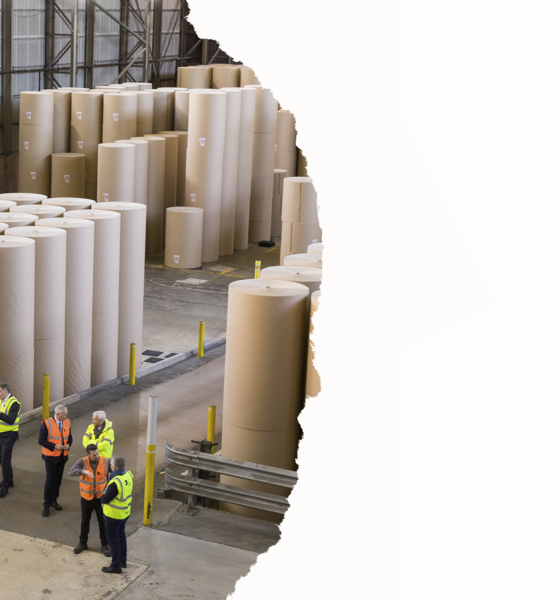 People standing next to giant reels of paper
