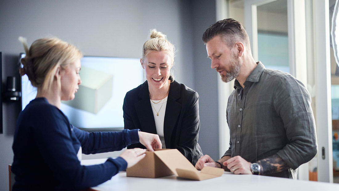 Kuvassa kolme ihmistä tutkii pakkausta ja innovoi uusia ratkaisuja.