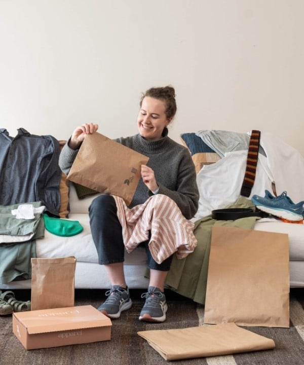 Eine Frau packt Pakete auf dem Sofa aus.