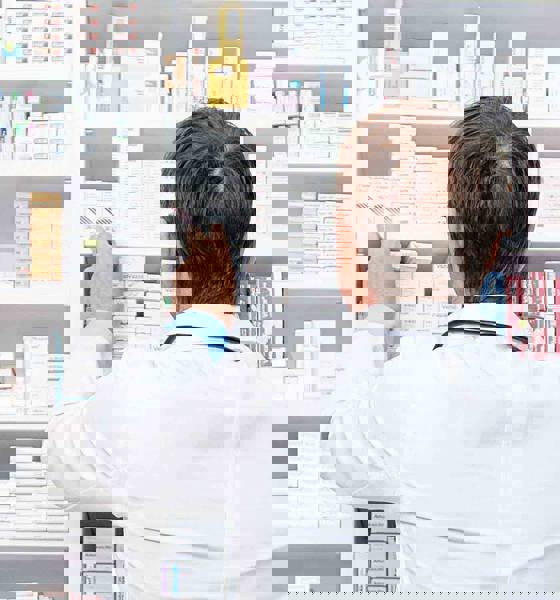 apoteker foran hylder med medicin