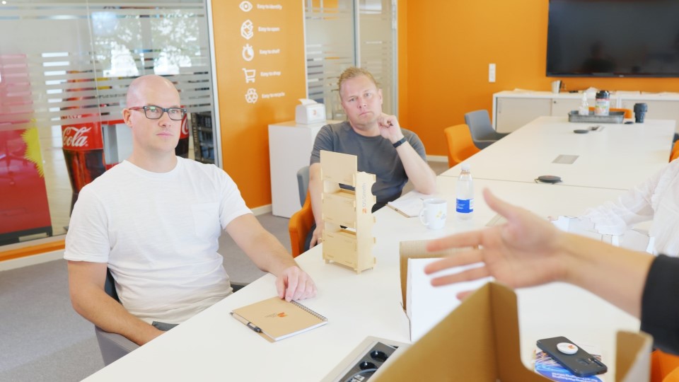 Zwei Kollegen sitzen am Tisch und hören gespannt zu.