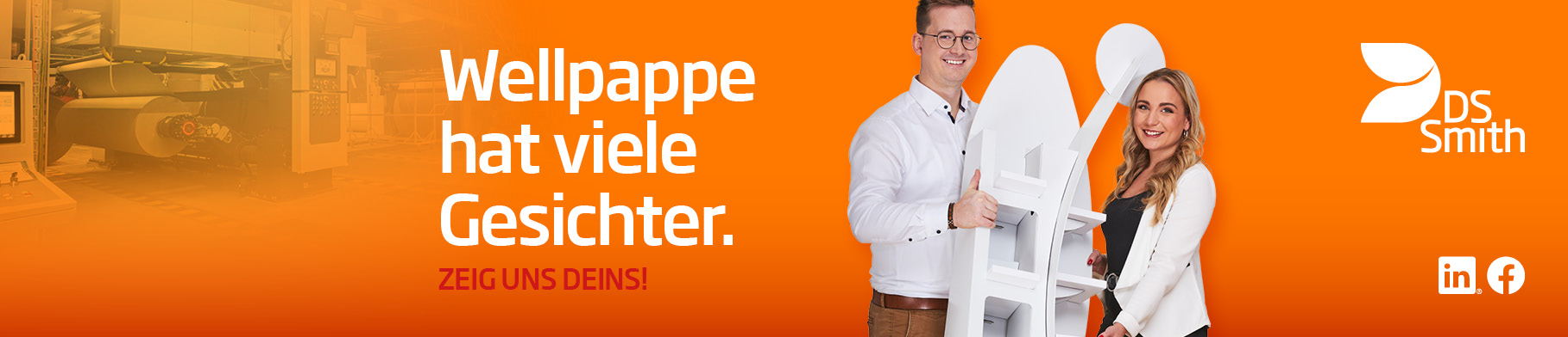 junger dunkelhaariger Mann mit weißem T-Shirt vor orangefarbenen Hintergrund lächelt in die Kamera und hält neben einem Kartonstapel einen kleinen Wellpappkarton in der Hand