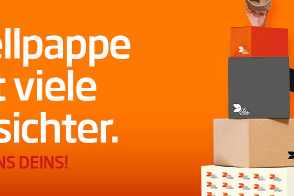 junge blonde Frau in dunklem Kleid steht rechts von einem Wellpappaufsteller und hält einen kleinen Wellpappkarton in der Hand und lächelt.