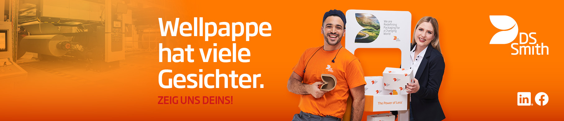 dunkelhaariger junger Mann steht links neben einem Aufsteller aus Wellpappe, freundlich in die Kamera lächelnd, mit einem kleinen Wellpappkarton in der Hand. Mütze und Gehörschutz und oranges T-Shirt, Arbeitskleidung, vor orangefarbenem Hintergrund. Rechts vom Auftseller steht eine junge blonde Frau mit langen Haaren und dunklem Jacket und lächelt in die Kamera