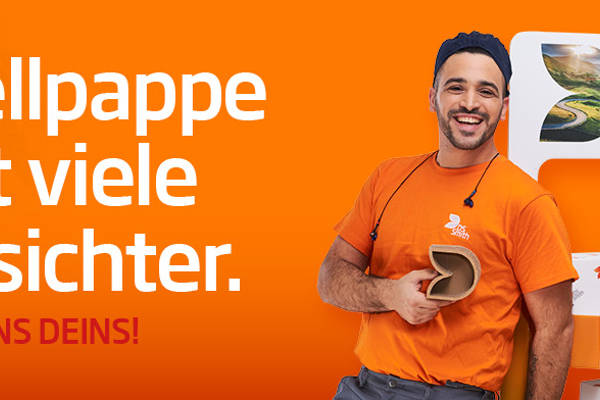 dunkelhaariger junger Mann steht links neben einem Aufsteller aus Wellpappe, freundlich in die Kamera lächelnd, mit einem kleinen Wellpappkarton in der Hand. Mütze und Gehörschutz und oranges T-Shirt, Arbeitskleidung, vor orangefarbenem Hintergrund. Rechts vom Auftseller steht eine junge blonde Frau mit langen Haaren und dunklem Jacket und lächelt in die Kamera