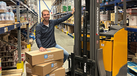 Medewerker Butlon met dozen bij heftruck in magazijn