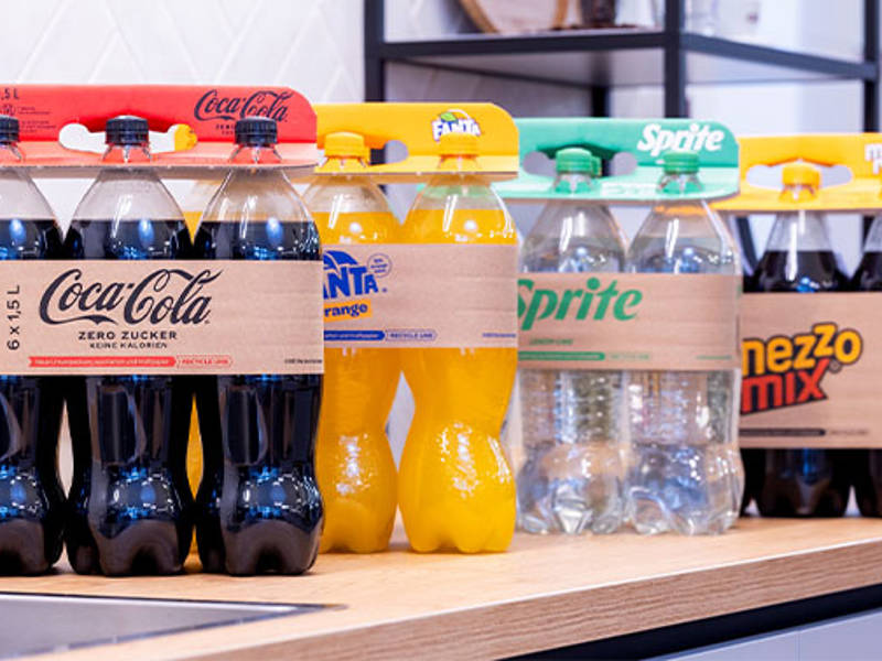 Flessen frisdrank, Coca-Cola, Fanta, Sprite, handvat van golfkarton in supermarktschap