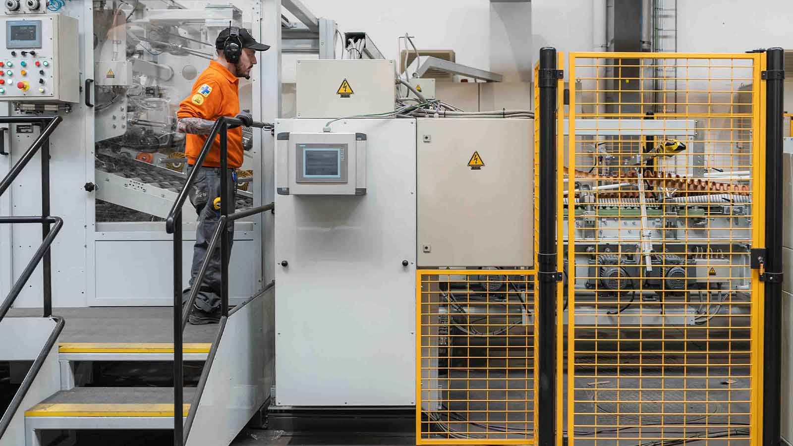 Een man staat op een trap voor een verwerkingsmachine voor golfkartonnen verpakkingen bij DS Smith in Harelbeke