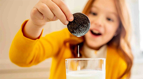Girl dipping Oreo cookie in milk
