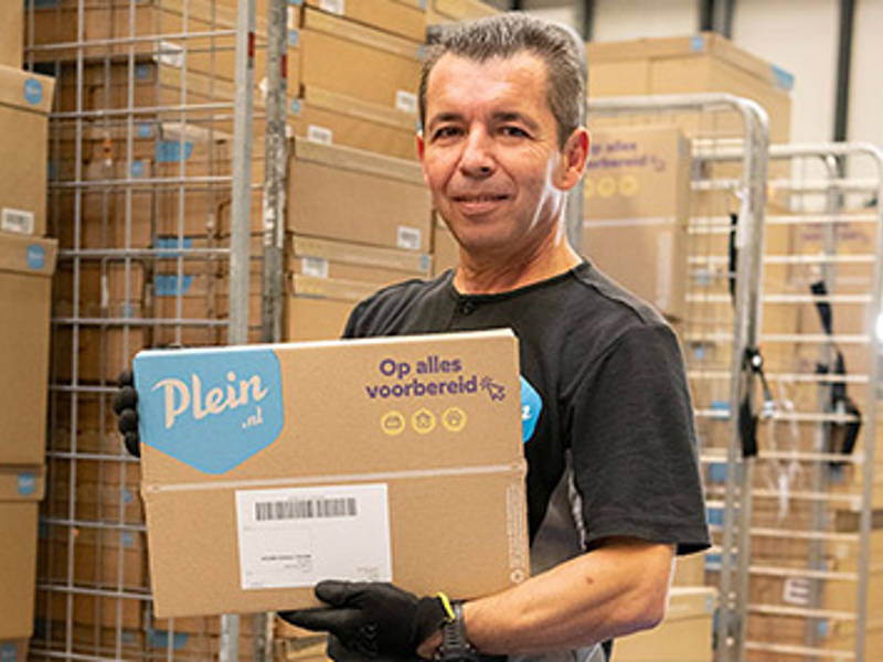 Medewerker van Plein in magazijn met bruine e-commerce verpakking