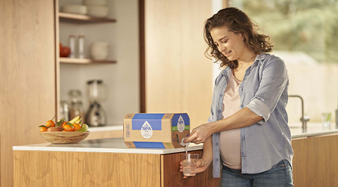 Vrouw tapt water uit bag-in-box in de keuken
