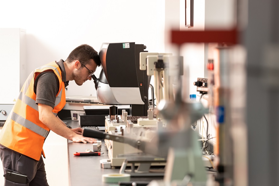 DS Smith lab technician looking into a machine to test the quality of packaging material